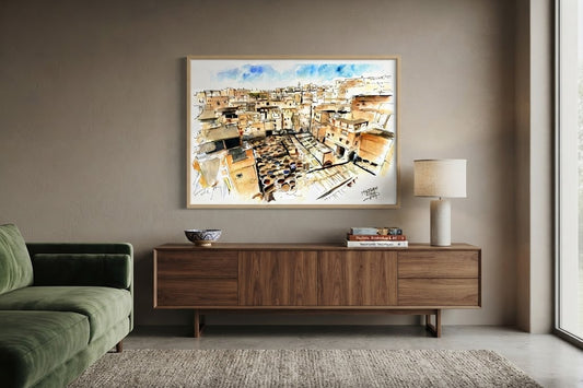 Tableau encadré de l'aquarelle « Les Cuves de Fès », accroché au mur au-dessus d'un meuble en bois bas dans un salon moderne aux teintes neutres.