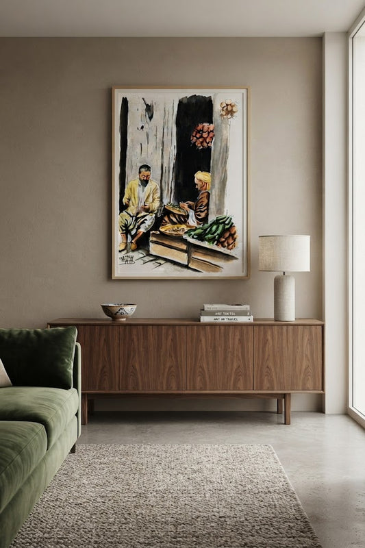 Tableau encadré de l'aquarelle « Les Marchands du Souk », accroché au mur au-dessus d'un meuble en bois bas dans un salon moderne aux teintes neutres.