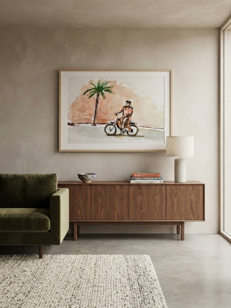 Tableau encadré de l'aquarelle « Échappée sous le Palmier », accroché au mur au-dessus d'un meuble en bois bas dans un salon moderne aux teintes neutres.