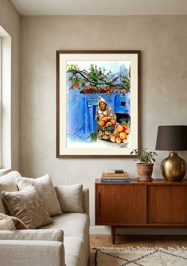 Tableau encadré représentant l'aquarelle Le Marchand d'Oranges de Chefchaouen, accroché au-dessus d'un buffet en bois dans un salon moderne.