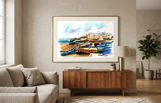 Tableau encadré représentant l'aquarelle Les Barques Bleues d'Essaouira, accroché au-dessus d'un meuble en bois dans un salon moderne.